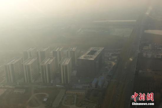 　　12月16日，透過飛機(jī)舷窗俯瞰北京，城市建筑隱在霧霾中。12月15日北京發(fā)布今年首個(gè)空氣重污染紅色預(yù)警：16日20時(shí)，北京市啟動(dòng)空氣重污染紅色預(yù)警。中新社記者 盛佳鵬 攝