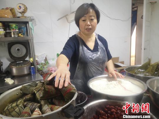 鄭春玲將兩張大粽葉窩成漏斗狀，填上糯米，放上兩粒紅棗，再加一片小粽葉，用棉線纏繞綁好，一個(gè)紅棗粽就成了，用時(shí)僅8秒?！「呖档?攝